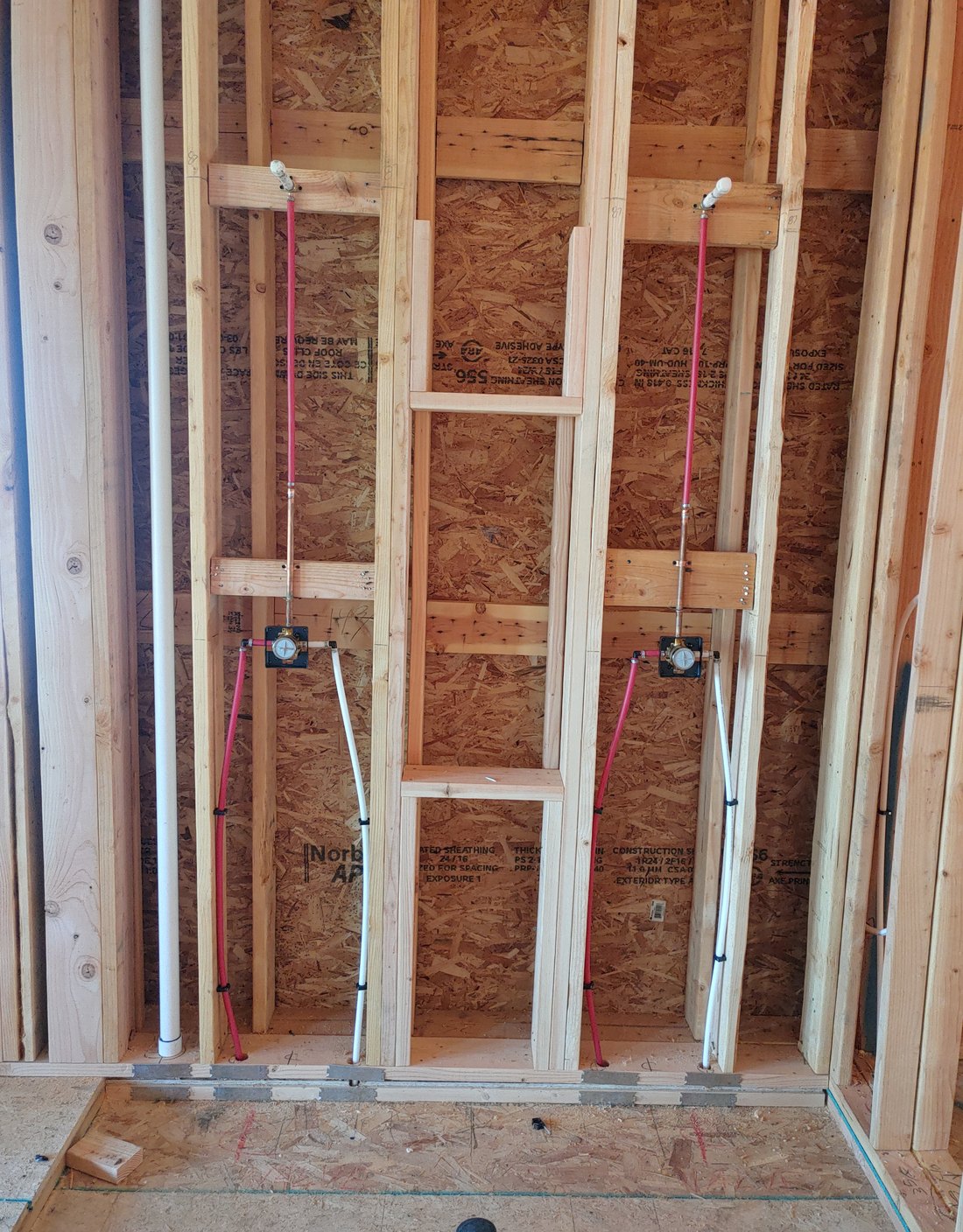 Red and white PEX water lines roughed in through wall framing, new construction in Middleton, Idaho
