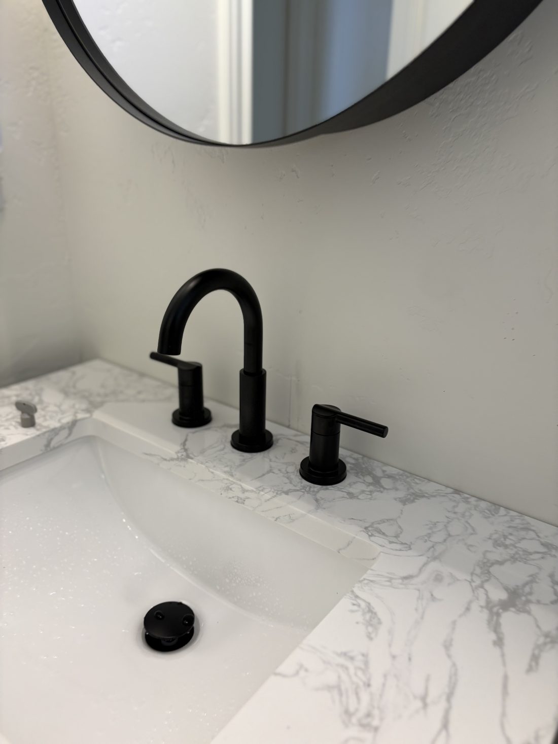 Black widespread faucet and drain set installed by S&K on a marble vanity in Meridian, Idaho